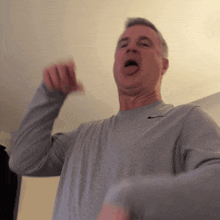 a man wearing a grey nike shirt is making a funny face