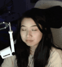 a woman with her eyes closed is sitting in front of a shure microphone