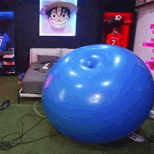 a blue ball with a hole in the middle is in a bedroom with a picture of monkey d luffy on the wall