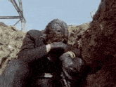 a man in a suit and gloves is sitting in a hole