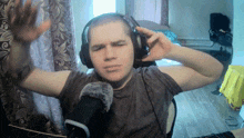 a man wearing headphones is sitting in front of a microphone with his hands in the air