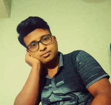 a young man wearing glasses and a striped shirt is looking at the camera
