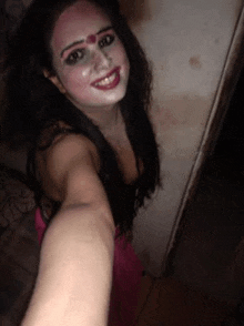 a woman with makeup on her face is taking a selfie with her hand .