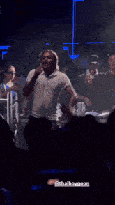 a man in a white shirt is singing into a microphone in front of a crowd with the hashtag thaiboygoon