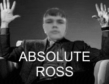 a man in a suit and tie is sitting in a chair with his hands up and the words `` absolute ross '' above him .