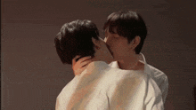 two men are kissing each other in front of a wall .
