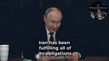 a man sitting at a table with a sign that says " under the famous agreement that we just mentioned " on it
