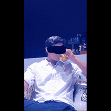 a man in a white shirt is drinking from a glass with his face obscured