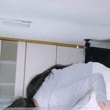 a woman in a grey shirt is laying on her back in a kitchen