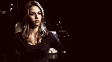 a woman in a dark room with a purple shirt on