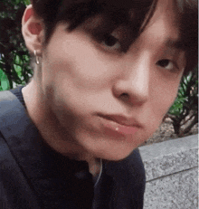 a close up of a young man 's face with a piercing in his lip and earring .
