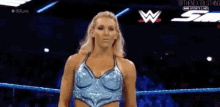 a woman in a blue dress is standing in a wrestling ring .
