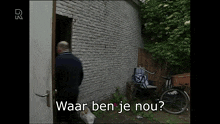 a man standing in front of a brick wall with the words waar ben je nou written on the bottom