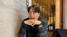 a man in a plaid shirt is sitting at a table with his hands on his mouth .