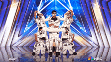a group of people dancing on a stage with a nbc logo in the corner