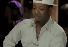a man wearing a hat and a necklace is sitting in a room .