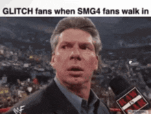 a man in a suit is talking into a microphone with the words glitch fans when smg4 fans walk in below him