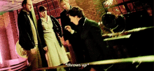 a group of people are standing around a man who is throwing up .