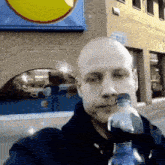 a bald man is drinking from a plastic bottle