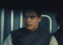 a man in a black vest is making a face