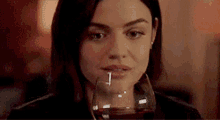 a woman is holding a glass of red wine in her hand .