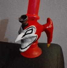 a red pipe with a clown face painted on it is sitting on a couch .