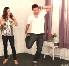 a man and a woman are dancing in a room with purple curtains