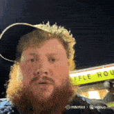 a man with a beard stands in front of a waffle house sign