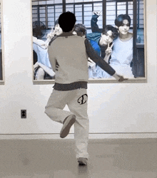 a man is dancing in front of a large picture of a group of men .