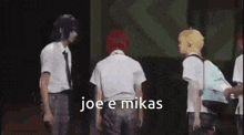 a group of people are standing on a stage with the words `` joe e mikas '' written on the bottom .