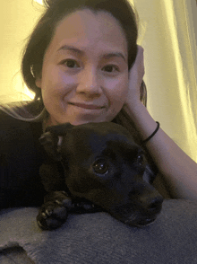 a woman laying on a blanket with a black dog on her lap