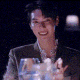 a man in a suit is smiling while holding a glass in his hand .