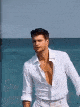 a man in a white shirt is standing on a beach .
