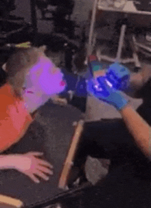 a person is laying on a table with a purple light shining on their face .