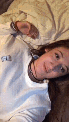 a woman is laying on a bed wearing a white shirt with a tennis court on it