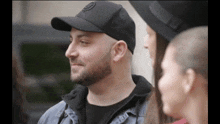 a man with a beard wears a black hat with the letter o on it