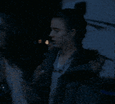 a woman in a fur vest stands next to another woman in a dark room