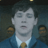 a close up of a man 's face wearing a blue jacket and a yellow tie