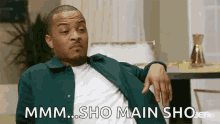 a man in a green jacket is sitting in a living room with his hand on his knee and says mmm sho main sho .