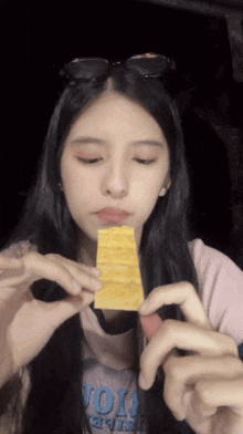 a girl wearing sunglasses is holding a piece of food in her hands
