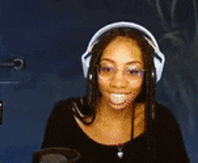a woman wearing headphones and glasses is smiling in front of a microphone