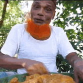 a man with a red beard is eating food from a green plate .