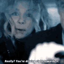 a woman is driving a car and talking to a man in the car .
