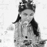 a woman wearing glasses is looking at a cell phone with math equations written on the wall behind her