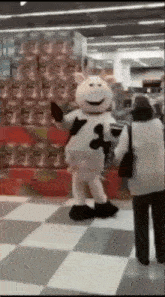 a person in a cow costume is dancing in a store