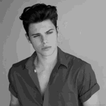 a black and white photo of a young man wearing a shirt and looking down .