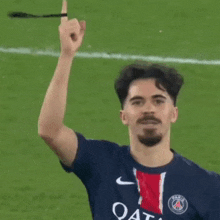 a soccer player wearing a qatar shirt holds up his finger