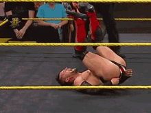 a wrestler is laying on his back in the ring during a match .