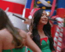 a woman in a green dress is smiling in front of a candy cane
