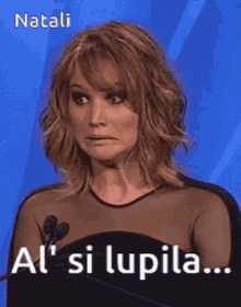 a woman in a black dress stands in front of a microphone and says al ' si lupila